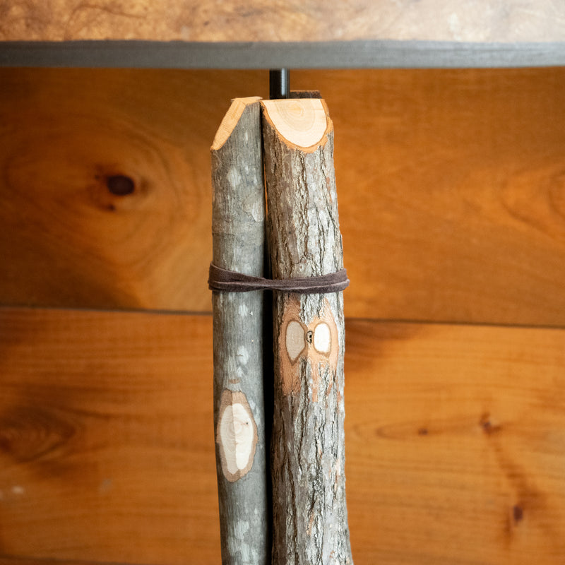 Close-up of the column of a rustic bundled wood tall table lamp against a rustic wooden wall