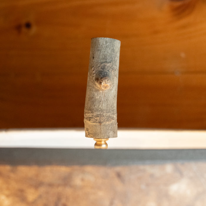 Close-up of the finial on a rustic bundled wood tall table lamp against a rustic wooden wall