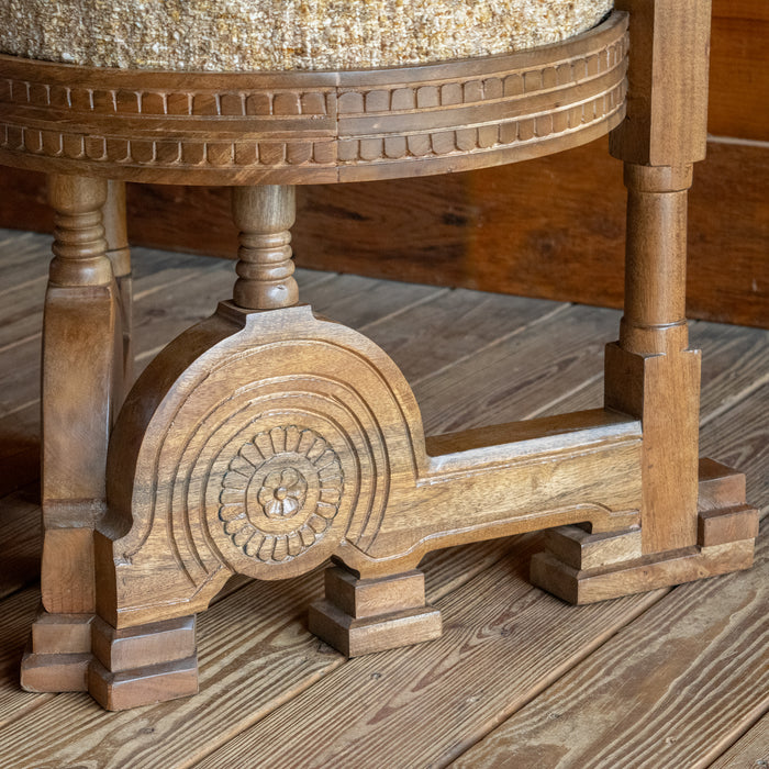 Close-up of the base of a sculptural accent chair inspired by an early 1900s Italian design against a wooden floor