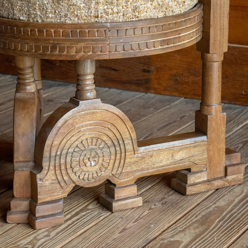 Close-up of the base of a sculptural accent chair inspired by an early 1900s Italian design against a wooden floor