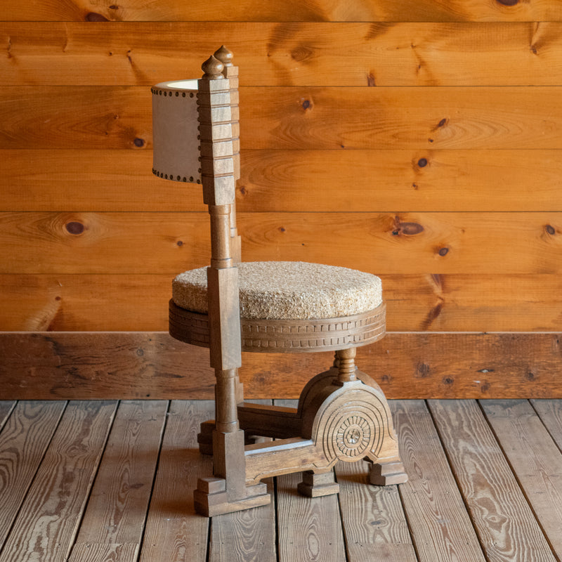 Profile view of a sculptural accent chair inspired by an early 1900s Italian design against a wooden wall