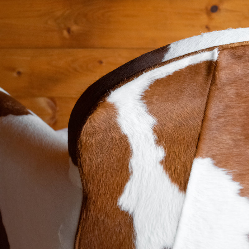 Close-up of the back of a cowhide leather chair against a wooden wall