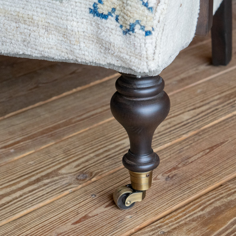 A close-up of the chair leg with a caster on a wooden floor