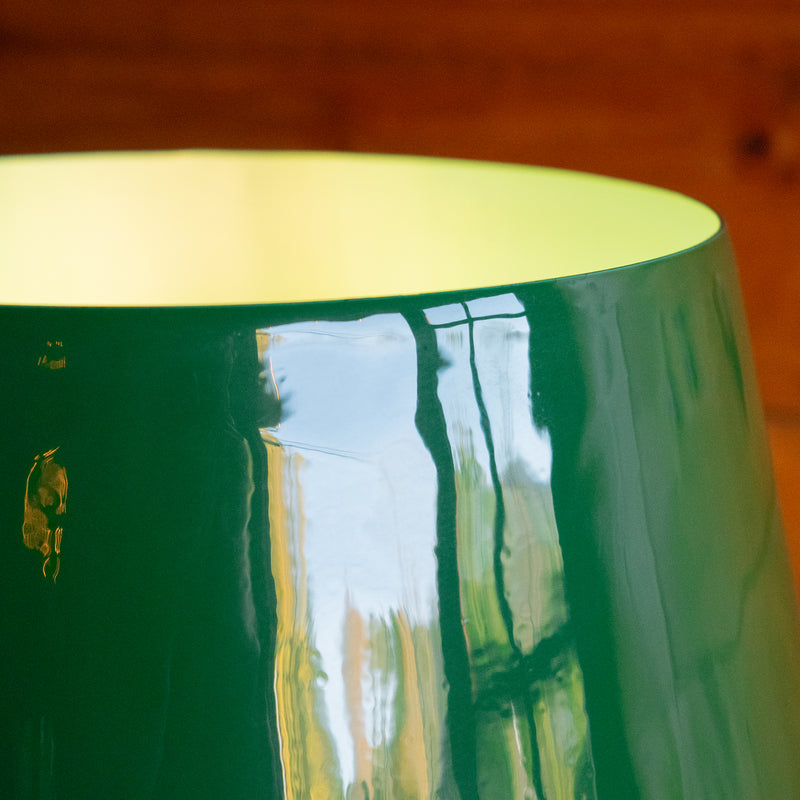 A close-up of the enamel shade of an emerald green table lamp