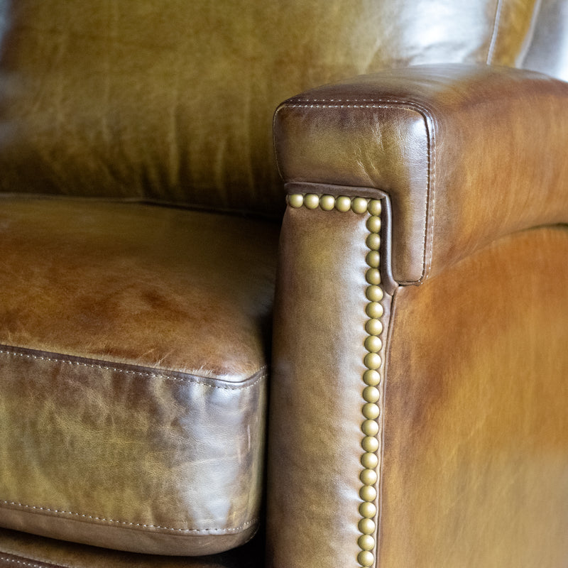 Close-up of the arm of an olive green leather swivel chair