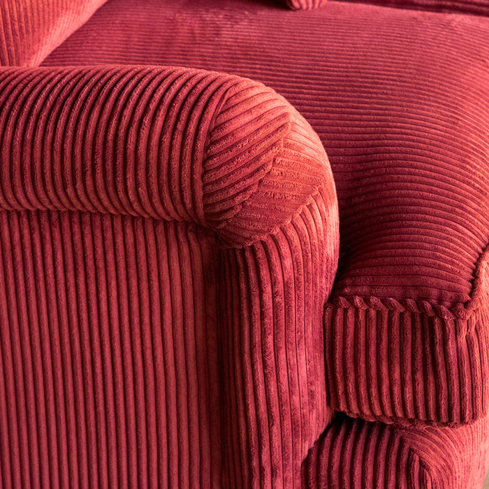 Close-up of a red corduroy velvet sofa English rolled arm and cushion