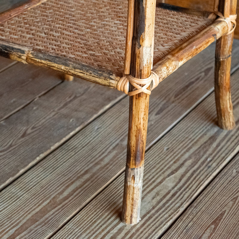 Close-up of the bamboo leg and woven shelf against a wooden floor. 