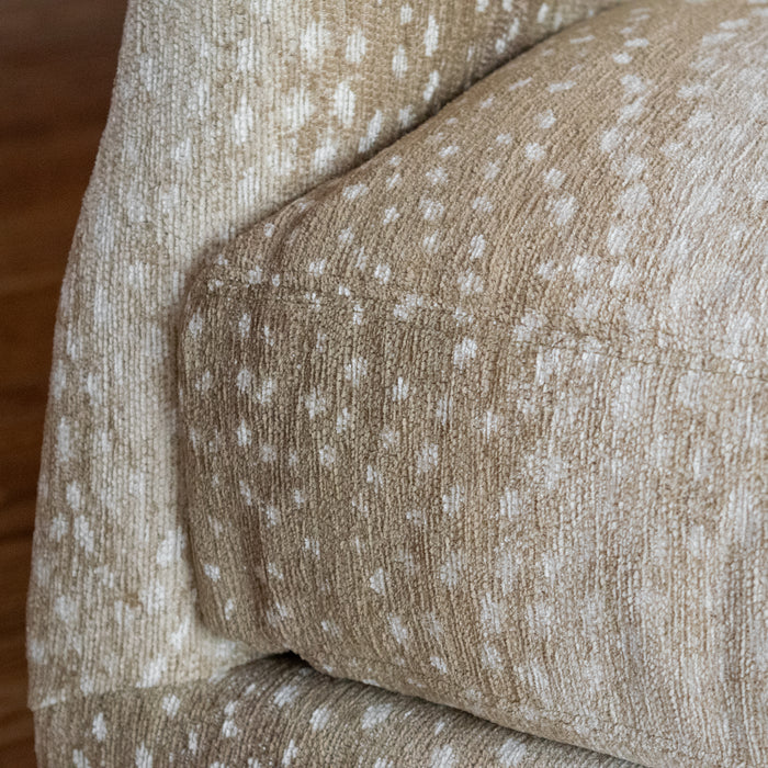 Close-up of the seat cushion of a sloped arm chair upholstered in a spotted antelope-inspired fabric 