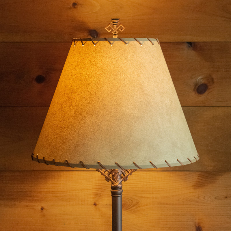 Close-up of a calfskin shade with leather lacing against a rustic wooden wall