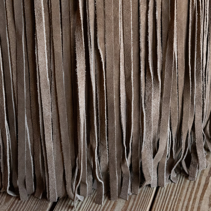 Close-up of the fringe on a rustic brown suede leather ottoman