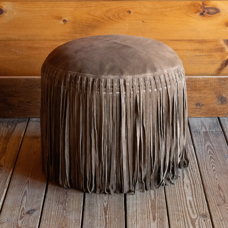 Close-up of the top of a rustic green suede leather ottoman