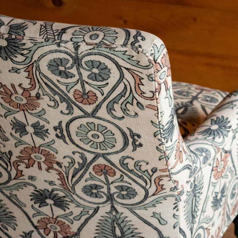 Close-up of the upper back of an upholstered chair, showing the bird and botanical block print pattern and the crisp tailoring of the tight back