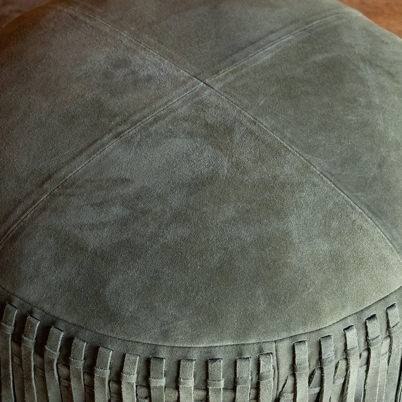 Close-up of the top of a rustic green suede leather ottoman