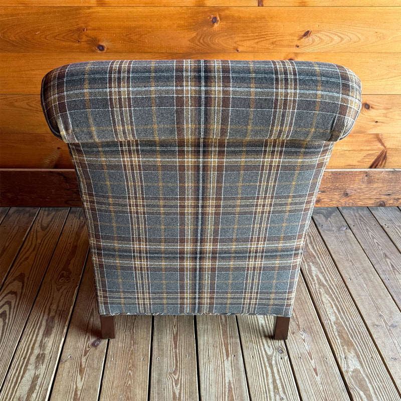 Back view of a steel blue, gold, and brown plaid armchair against a wooden wall