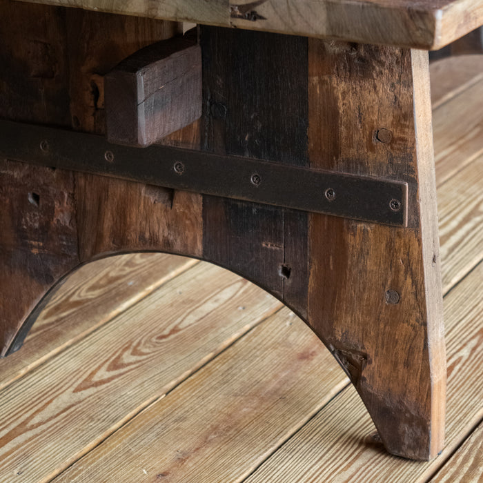 Close-up of the leg of a reclaimed teak wood coffee table on a wide-plank wooden floor