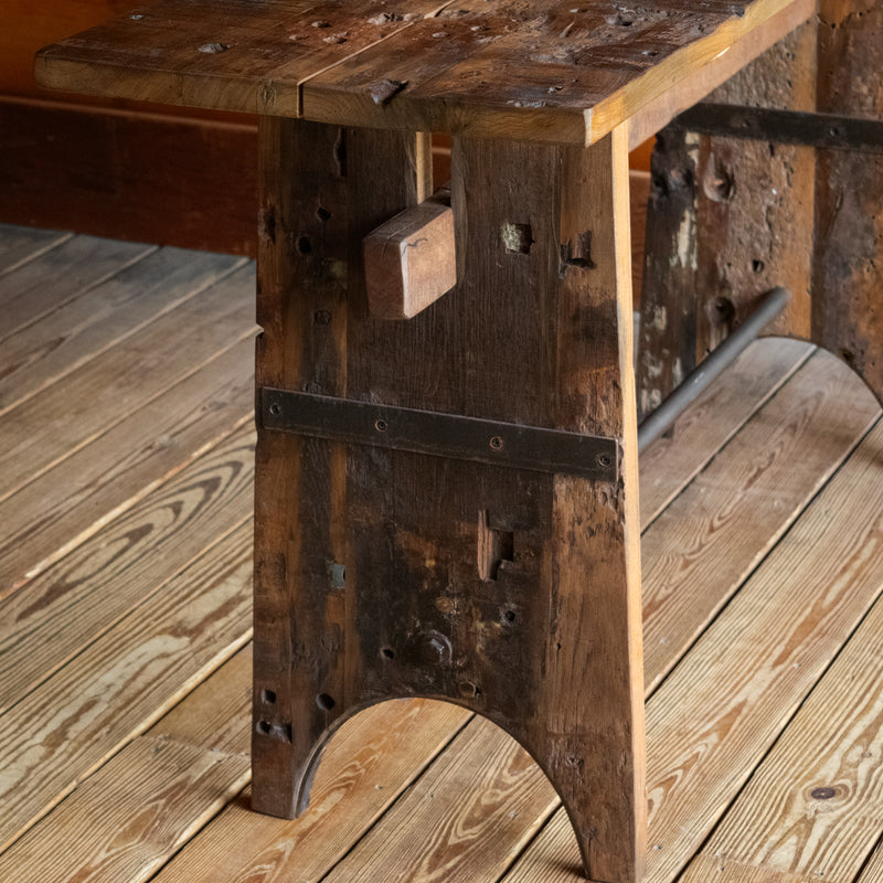 Close-up of the leg of a reclaimed teak wood console table on a wide-plank wooden floor