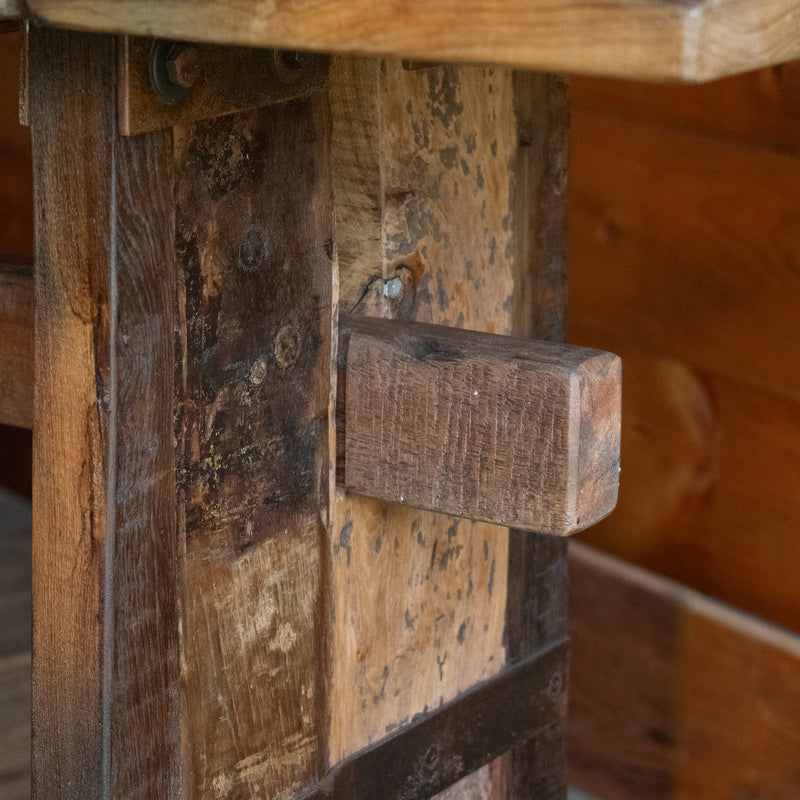 Close-up of the stretcher of a reclaimed teak wood console table against a rustic wooden wall 