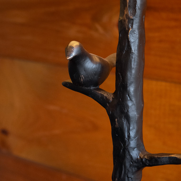 Close-up of the resin tree base of a rustic table lamp on a wooden side table against a rustic wooden wall