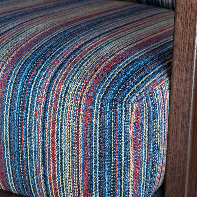 Close-up of an exposed wood frame chair and striped seat cushion