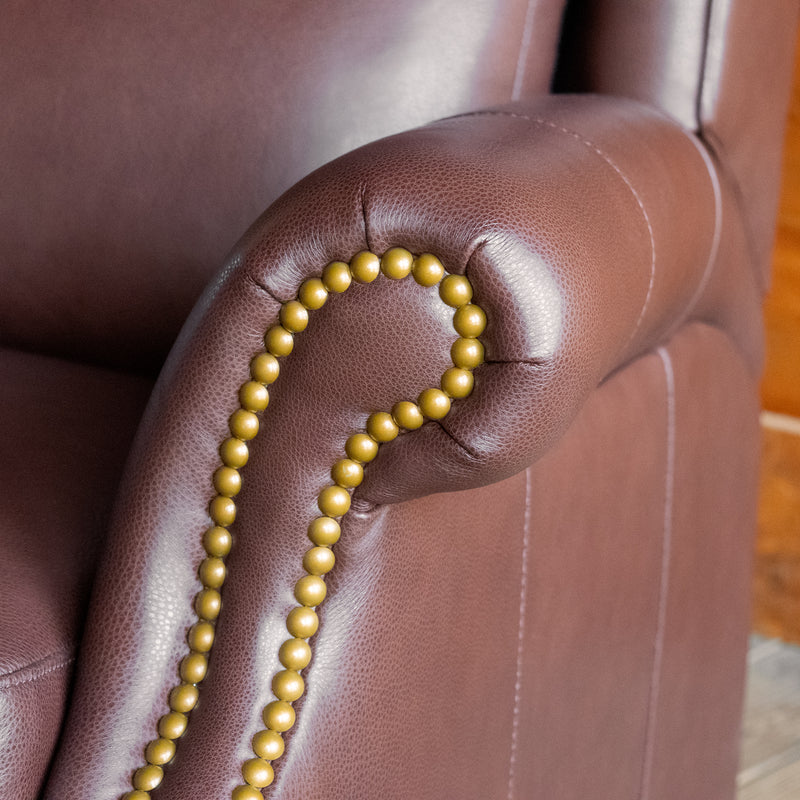 Rolled arm and nailhead trim close-up of a dark brown leather recliner