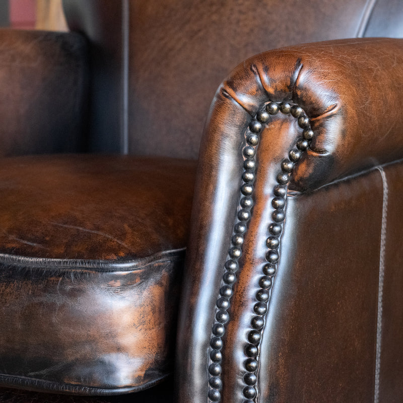 Close-up of the arm of a tight back rustic arm chair with nailhead trim