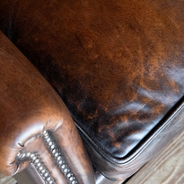 Close-up of seat cushion of a tight back rustic arm chair with nailhead trim