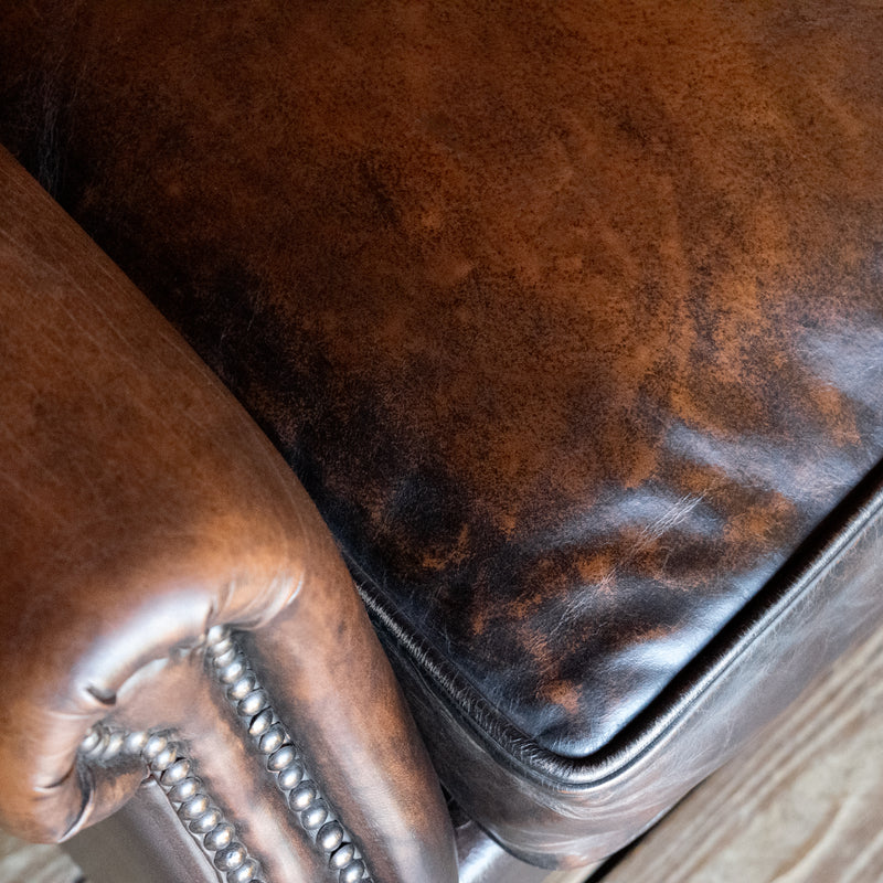 Close-up of seat cushion of a tight back rustic arm chair with nailhead trim