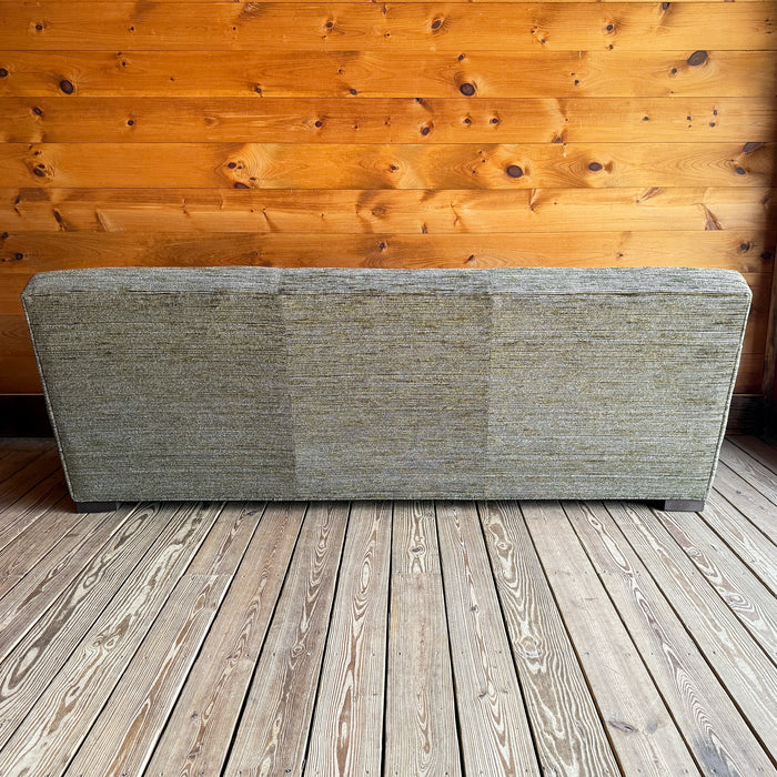 Back view of an 88" tight-back sofa upholstered in a mossy, mottled fabric against a wooden wall