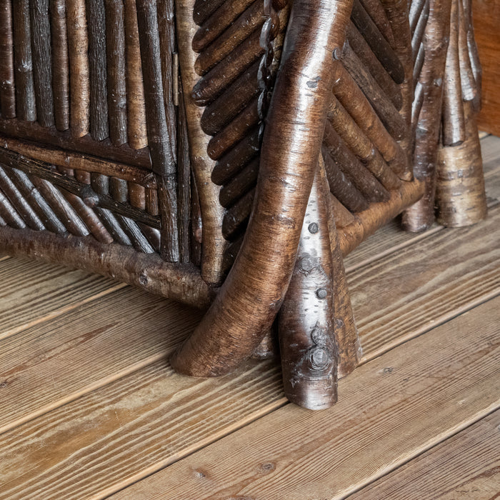 Close-up view of the log legs and mosaic twig work of an Adirondack style mosaic sideboard on a wide plank wooden floor