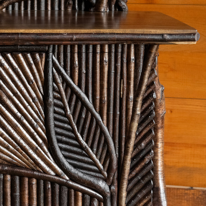Close-up view of the mosaic twig work of an Adirondack style mosaic sideboard against a rustic wooden wall