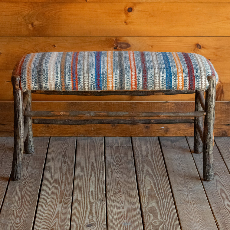 Close-up of the seat of a rustic hickory bench upholstered in a striped wool fabric